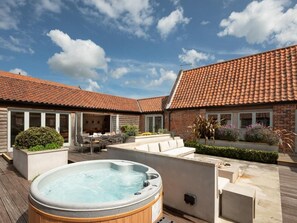 A patio with a hot tub, outdoor furniture, and a brick building with a tiled roof. - 4 Bed in Worstead (oc-65189) (Worstead)