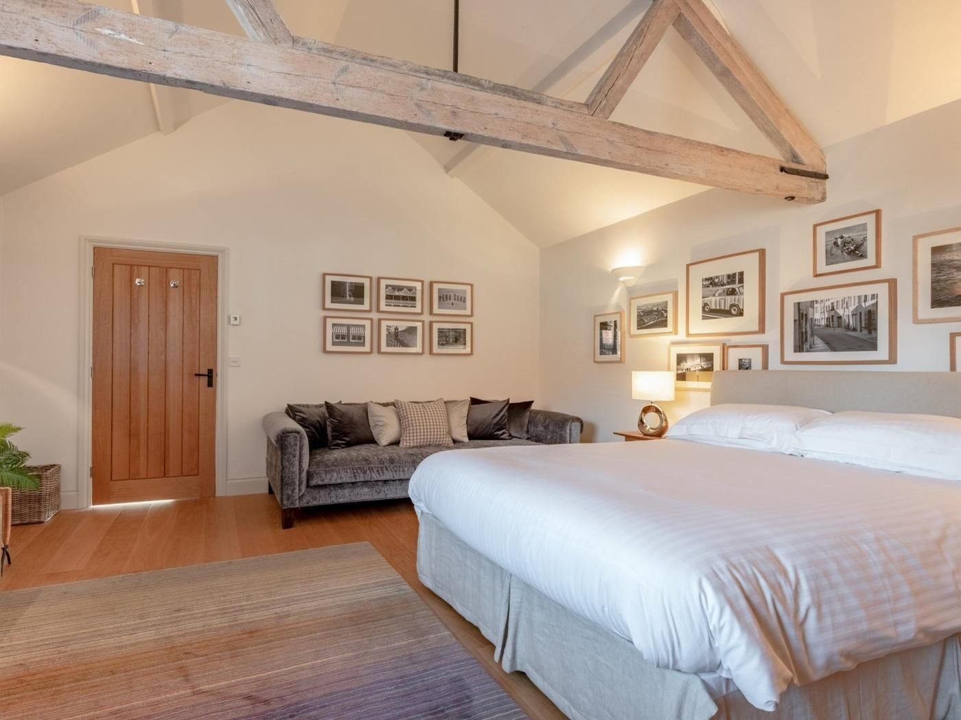 Ein Schlafzimmer mit einem Bett, einer Couch, einer Holzbalkendecke und gerahmten Bildern an der Wand.