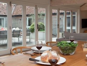 A dining table with a loaf of bread, two wine glasses, and a bowl of greens. - 4 Bed in Worstead (oc-65189) (Worstead)