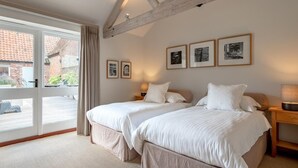 Een slaapkamer met twee bedden, een groot raam en een houten balk.