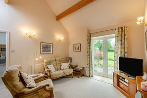 A living room with a sofa, armchairs, a television, and a large window with curtains. - 2 Bed in Harrogate (oc-hh087) (Beckwithshaw)