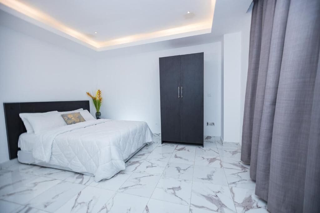 Une chambre à coucher avec un lit, une armoire et une table de chevet sur laquelle se trouve un vase.