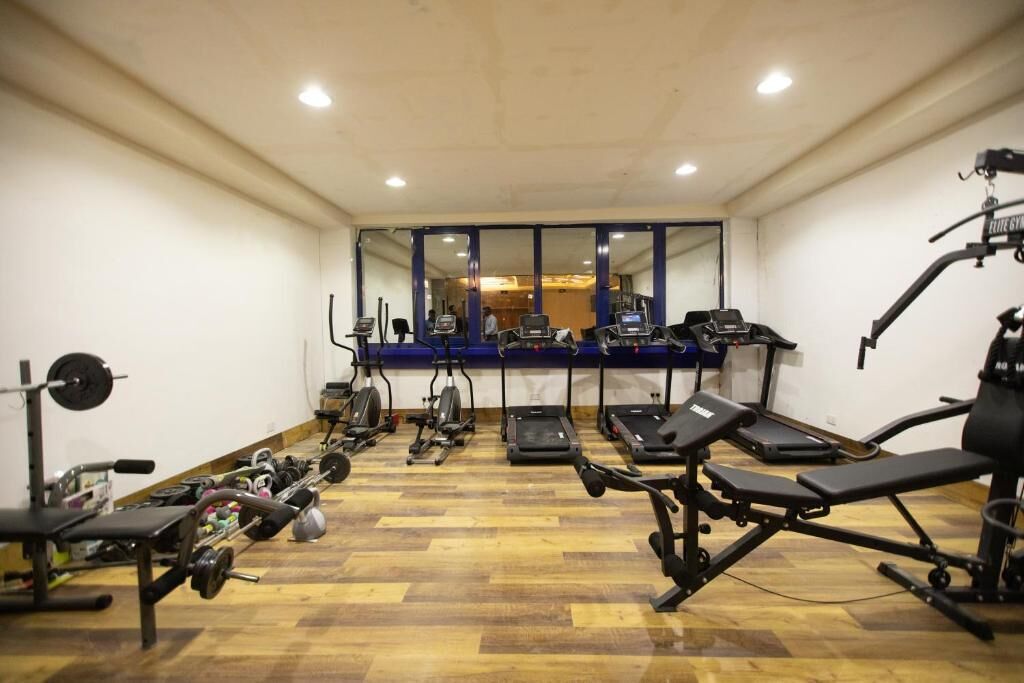 Une salle de sport équipée de tapis de course, de vélos elliptiques et de matériel de musculation.
