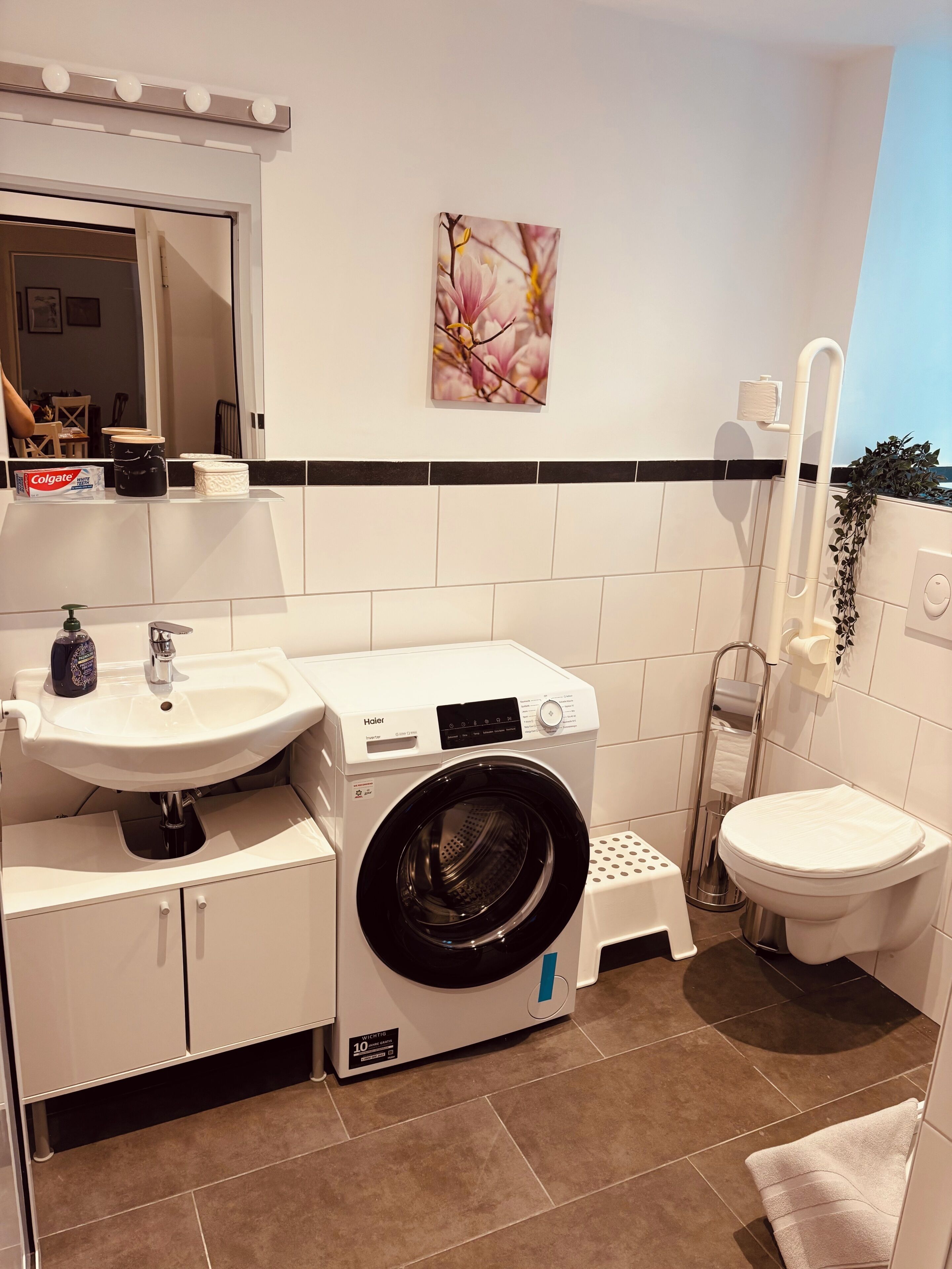 Ein kleines Badezimmer mit Waschbecken, Toilette und Waschmaschine.