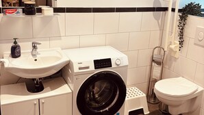Un bagno compatto con lavandino, water e lavatrice.
