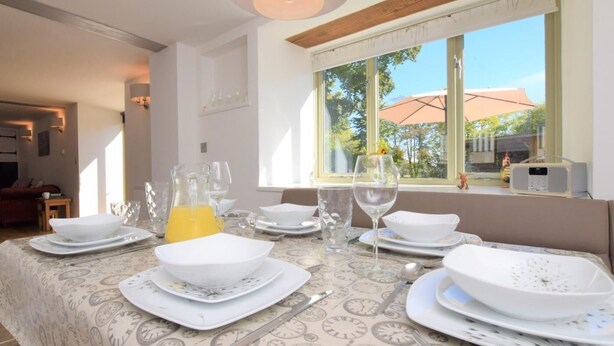 A dining table set with plates, glasses, and cutlery, a pitcher of juice, and a window with a view of the outdoors. - 3 Bed in North Tawton (oc-66043) (Bondleigh)