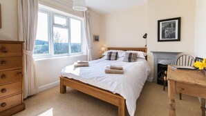 A bedroom with a wooden bed, a dresser, a fireplace, and a window with curtains. - 3 Bed in Harrogate (oc-hh057) (Harrogate)