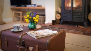 A vintage suitcase on a floor, a small table with a cup and a vase of flowers, and a television in the background. - 3 Bed in Harrogate (oc-hh057) (Harrogate)