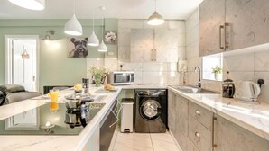 A modern kitchen with a central island, built-in appliances, pendant lighting, and a view into the dining area. - 1 Bed in Beccles (oc-65080) (Beccles)