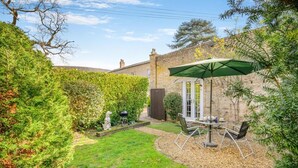 A backyard with a patio table and chairs, a barbecue grill, and a dog statue. - 1 Bed in Beccles (oc-65080) (Beccles)