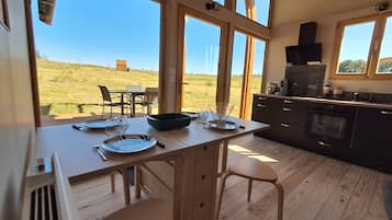 Een keuken met grote ramen, een eettafel gedekt voor twee personen, en uitzicht op de natuur.