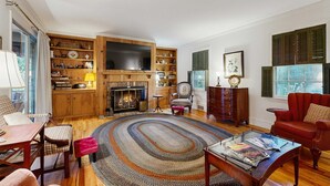 Una sala de estar con chimenea, estanterías, un televisor y un sillón rojo.
