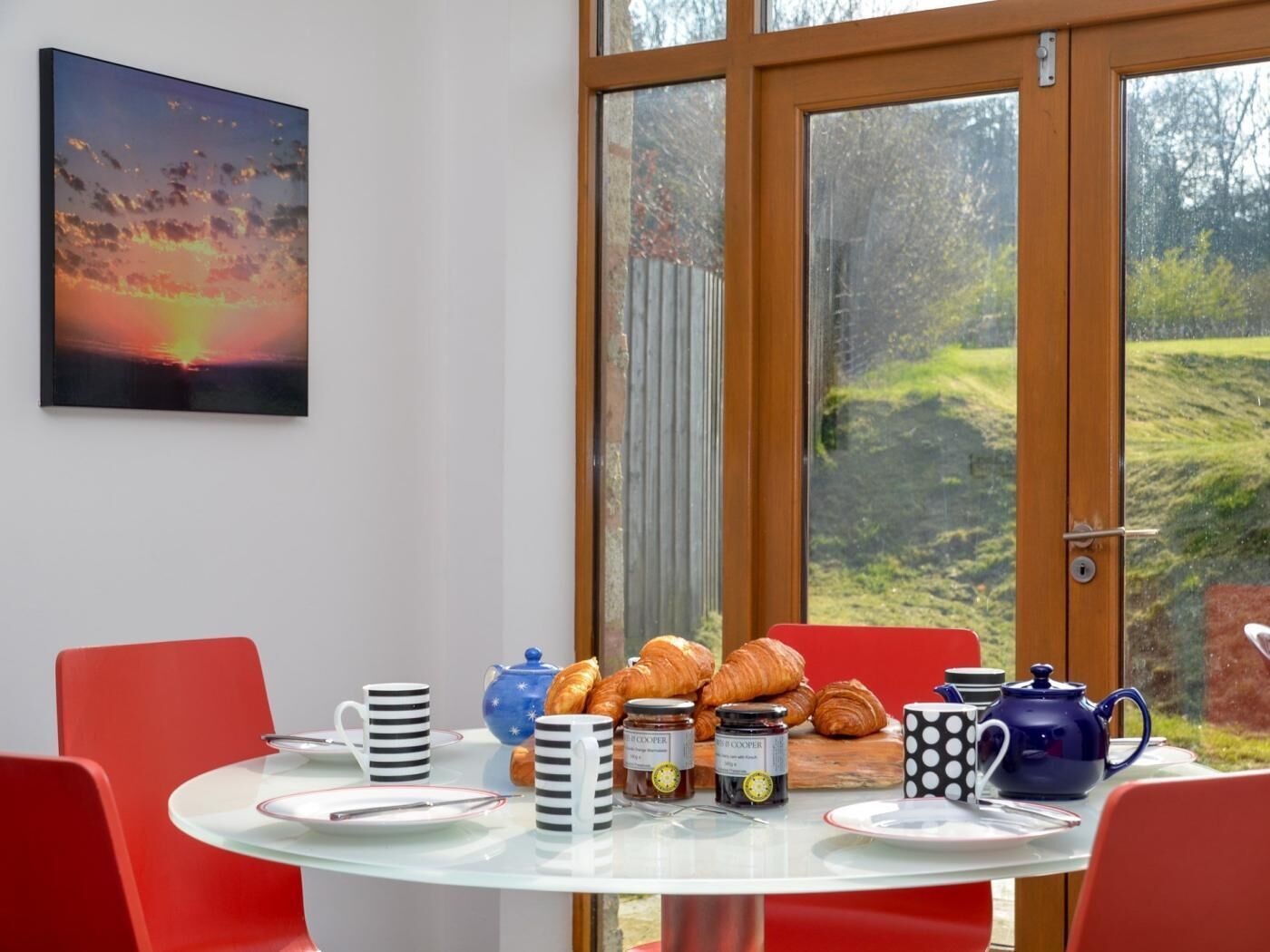 A breakfast table with croissants, coffee, and tea set.