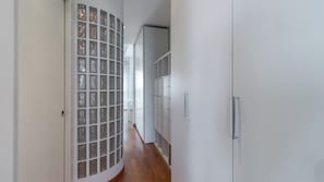Ein Korridor mit Glastrennwand, weißen Wänden und Holzboden.