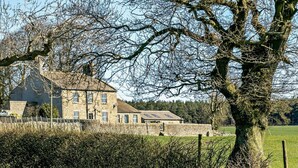 A stone house with a large lawn and a tree in the foreground. - 2 Bed in Harrogate (oc-hh018) (Lindley)