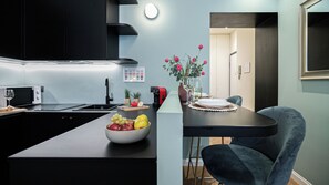 Eine moderne Küche mit einer zentralen Kochinsel, einem Essbereich mit Tisch und Stühlen sowie Blick in den angrenzenden Raum.