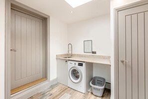 A laundry room with a washing machine, a sink, and a basket. - 3 Bed in Newton Abbot (oc-64380) (Bovey Tracey)
