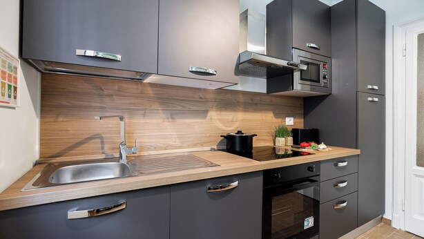 Eine moderne Küche mit Spüle aus Edelstahl, Holz Arbeitsplatte und eingebauten Geräten.