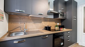 A modern kitchen with a stainless steel sink, wooden countertop, and built-in appliances. - Italianway Comfort - Da Messina 20 (Milano)