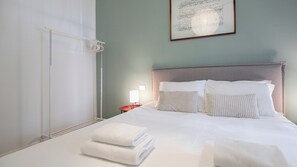 Ein Hotelzimmer mit Bett, Kissen, einem Nachttisch mit Lampe und einem Handtuch auf dem Boden.