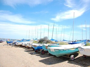 A row of boats with masts, docked on a gravel beach. - 4 Bed in Brancaster (oc-kt196) (Brancaster)