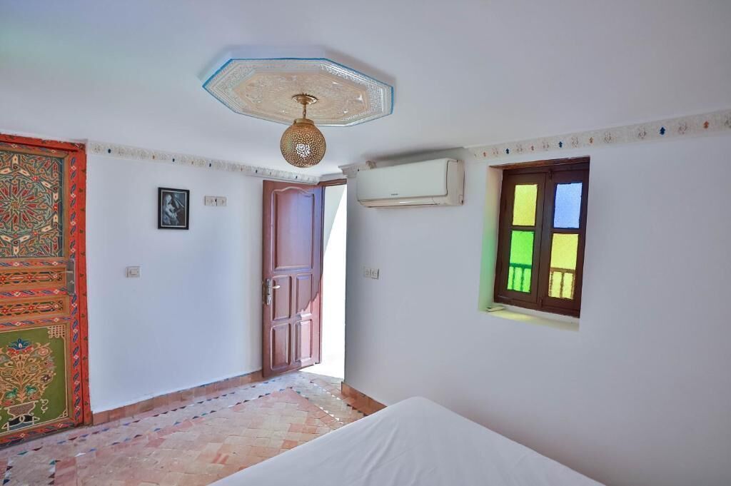 Una habitación con una cama, una puerta, un equipo de aire acondicionado y una ventana.