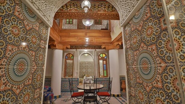 A room with a patterned tile floor, a wooden ceiling, and a central chandelier.