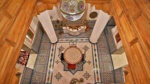 A room with a patterned floor, a central decorative element, and a chandelier.