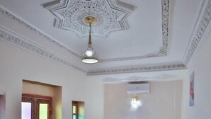 A bedroom with a bed, a sofa, a patterned rug, a decorative ceiling, and a door with intricate designs.