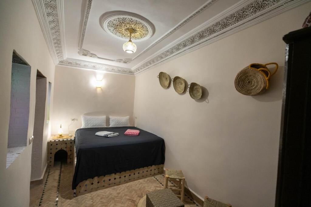 Une chambre à coucher comprenant un lit, une table de chevet, une lampe fixée au mur et un plafond décoratif.