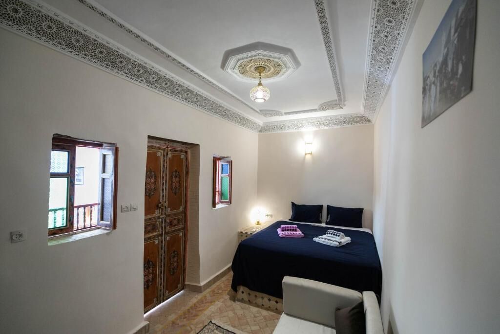 A bedroom with a bed, a desk, a chair, a wardrobe, and a window.
