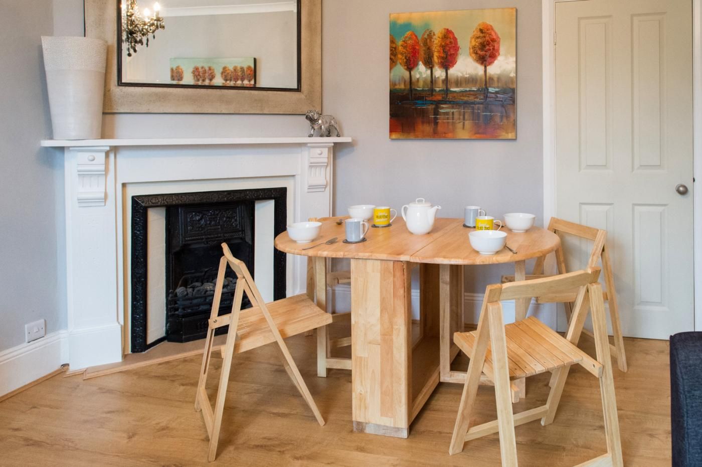 A dining area with a round wooden table, four chairs, and a fireplace.