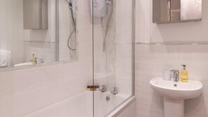Ein Badezimmer mit einer Duschkabine, einem Standwaschbecken und einem Spiegel darüber.