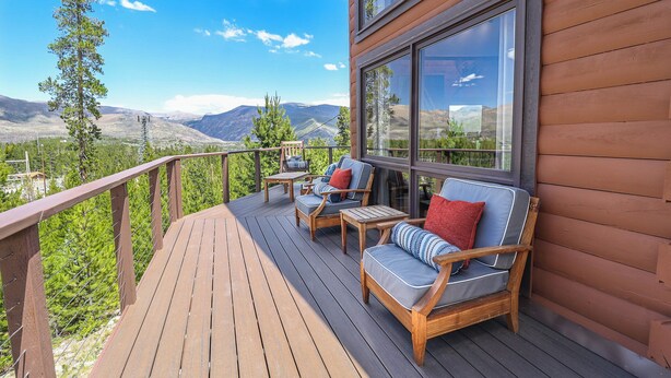 A wooden deck with outdoor furniture and a view of mountains.