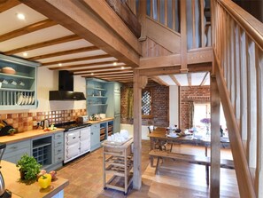 Eine Küche mit Holzbalken, ein Essbereich mit Tisch und Stühlen sowie eine Treppe.