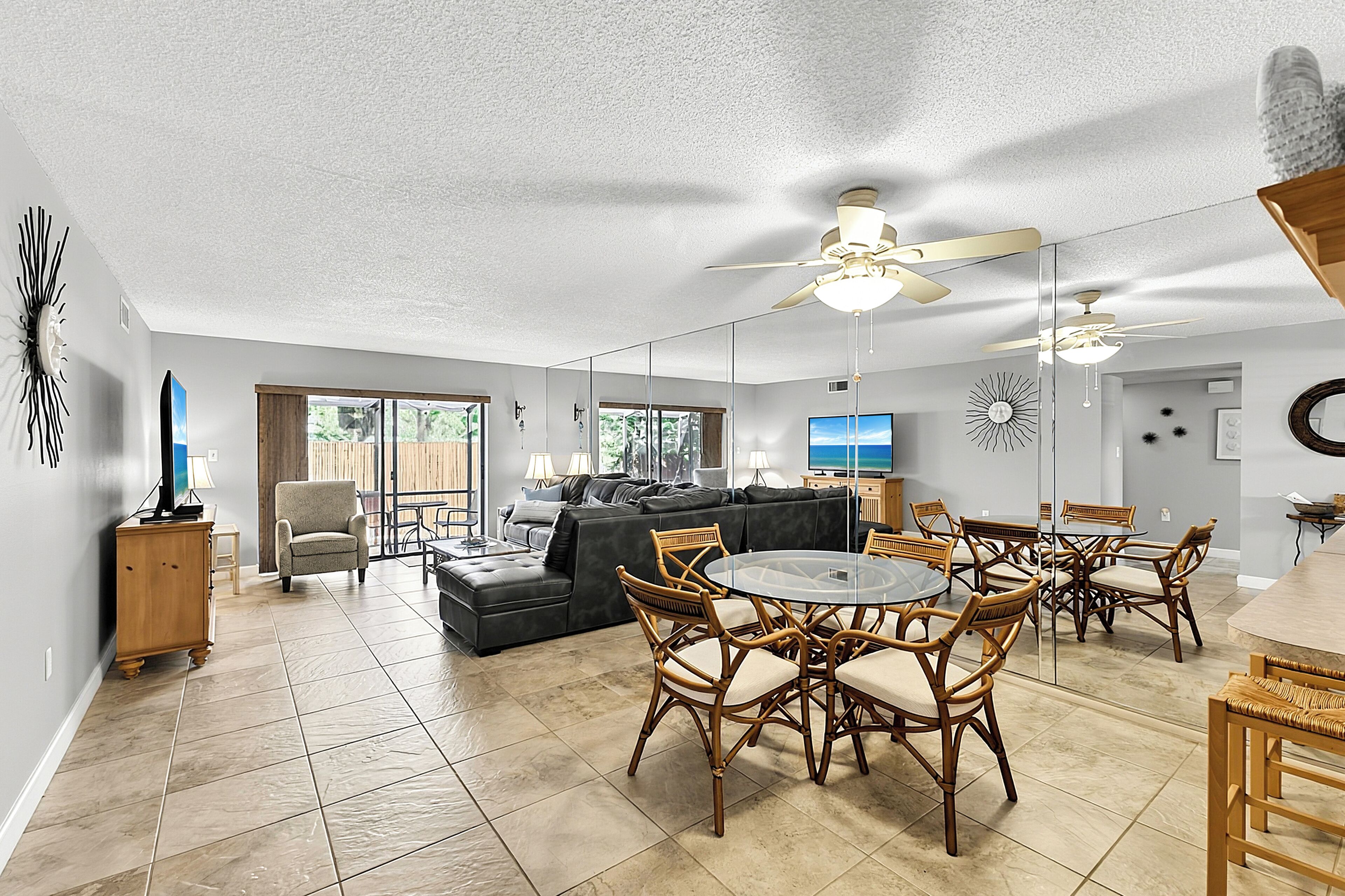 A spacious living area with a dining table, chairs, a sofa, and a ceiling fan.