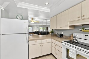 A kitchen with white cabinetry, a refrigerator, a stove, and a ceiling fan. - 1st floor walk to restaurants and beach (Siesta Key)