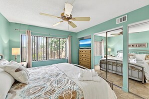 A bedroom with a bed, a dresser, a television, and a mirror. - 1st floor walk to restaurants and beach (Siesta Key)