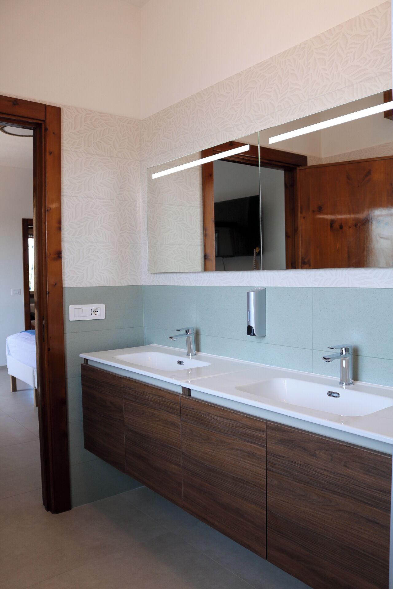 Un bagno moderno con due lavabi, uno specchio grande e mobili in legno.