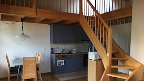 Eine Küche mit Holzschnitzschränken, einem Esstisch mit Stühlen und einer Holztreppe.