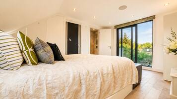 A bedroom with a large bed, multiple pillows, a wardrobe, a door, and a window with a view.