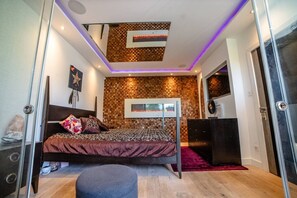 Ein Schlafzimmer mit einem Bett, einem Schreibtisch, einem an der Wand montierten Fernseher und einer Decke mit einem Schachbrettmuster.
