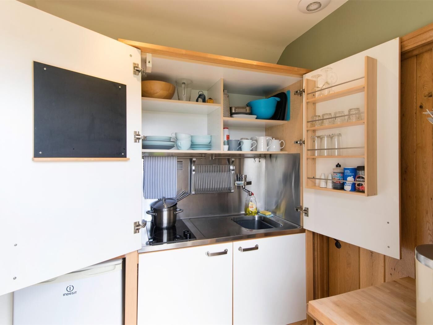 A compact kitchen with a sink, stove, and storage cabinets.