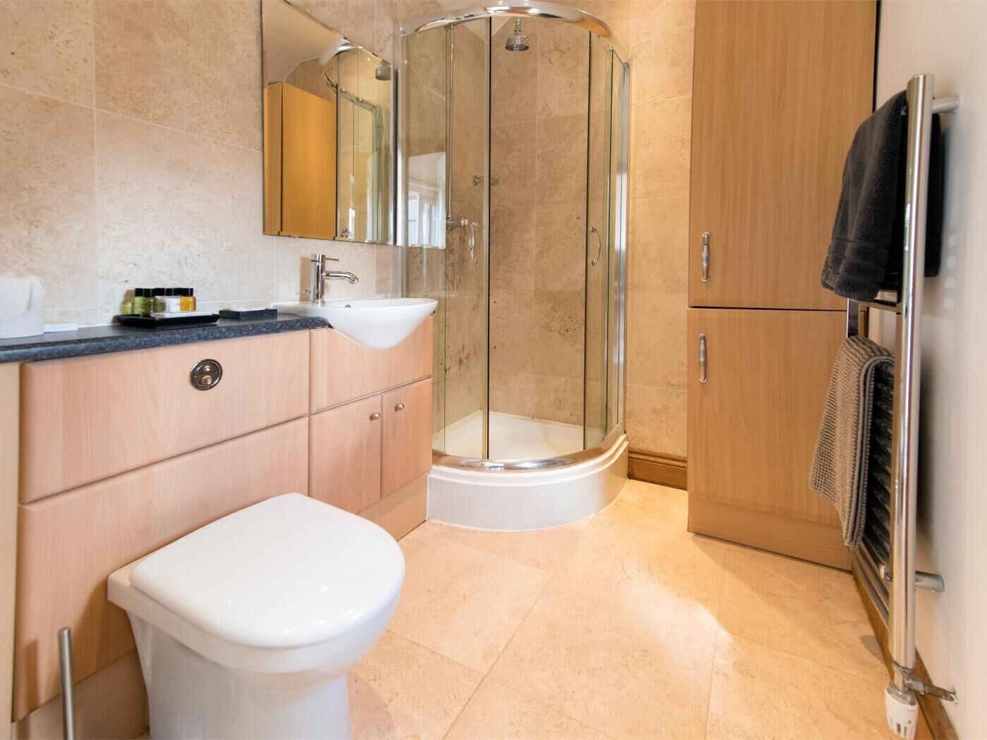 A modern bathroom with a glass-enclosed shower, a white toilet, a sink, and a wooden cabinet.