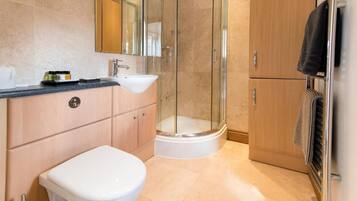 A modern bathroom with a glass-enclosed shower, a white toilet, a sink, and a wooden cabinet.