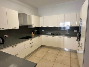 A modern kitchen with white cabinets, a black countertop, and a stainless steel sink. - Fort Cambridge - Sliema - Malta (Sliema)