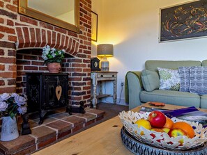 Ein gemütliches Wohnzimmer mit Kamin, Sofa, Lampe und Obstkorb.