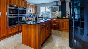 A kitchen with wooden cabinets, a black refrigerator, and a large island. - 3 Bed in Presteigne (oc-78350) (Kinsham)