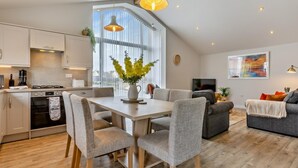 A modern kitchen with a dining area, a sofa, and a TV. - 3 Bed in Bideford (oc-64410) (Northam)