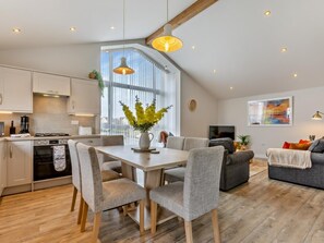 A modern kitchen with a dining area, a sofa, and a TV. - 3 Bed in Bideford (oc-64410) (Northam)